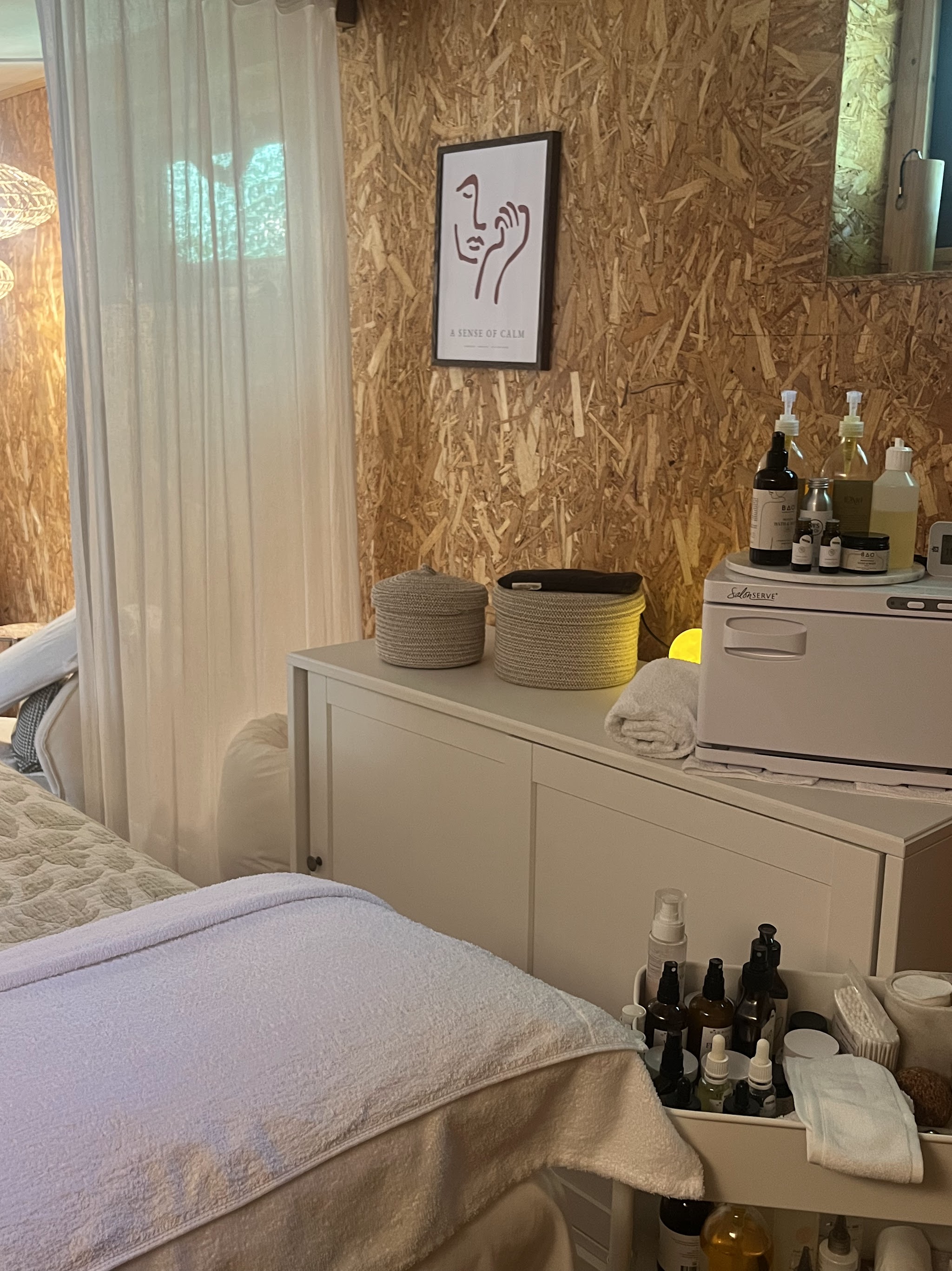 The treatment couch dressed in soft blankets beside a dresser of oils and warm towels