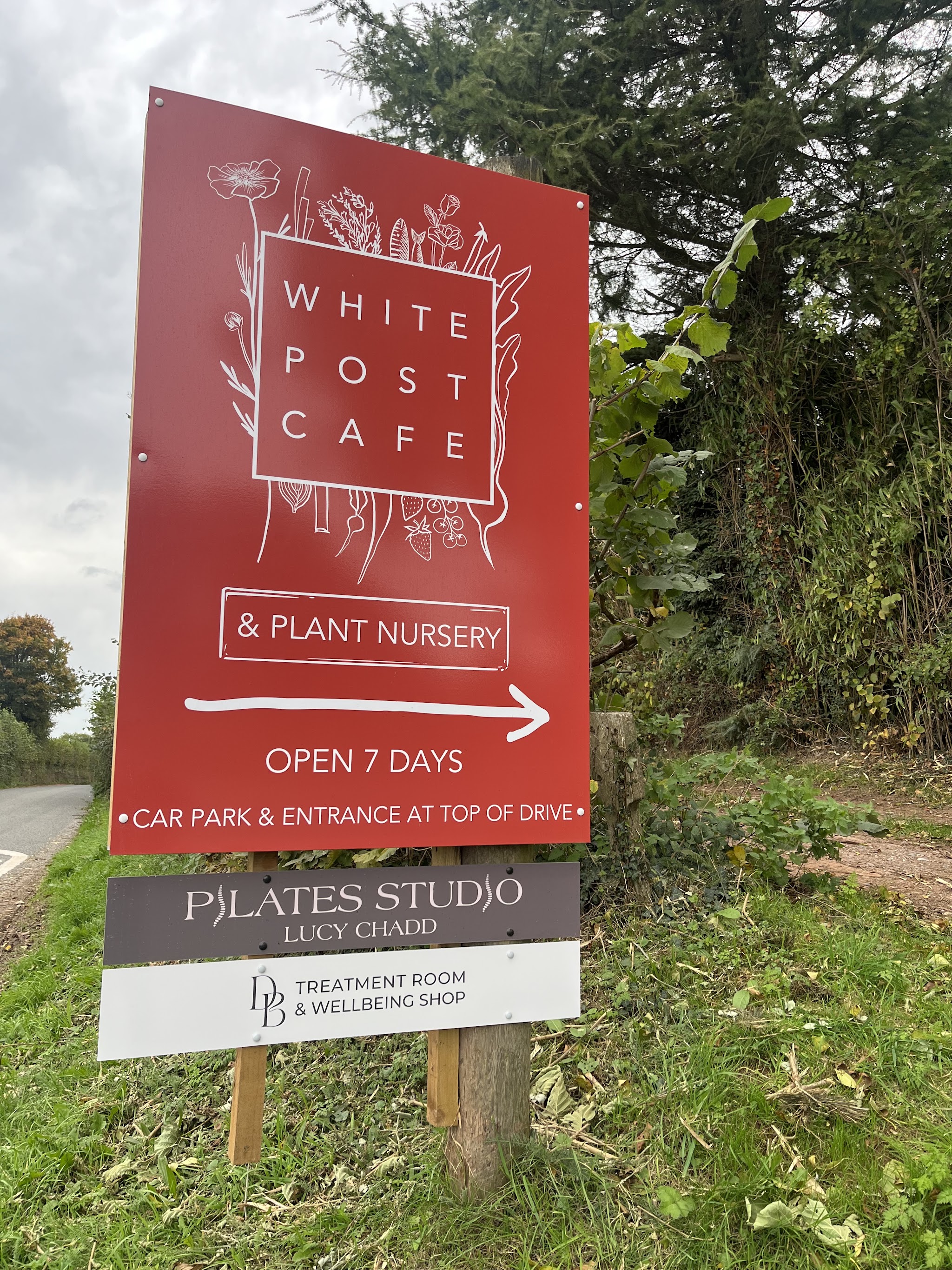 The White Post roadside sign, with the DB Treatment Room and Wellbeing Shop board at the bottom